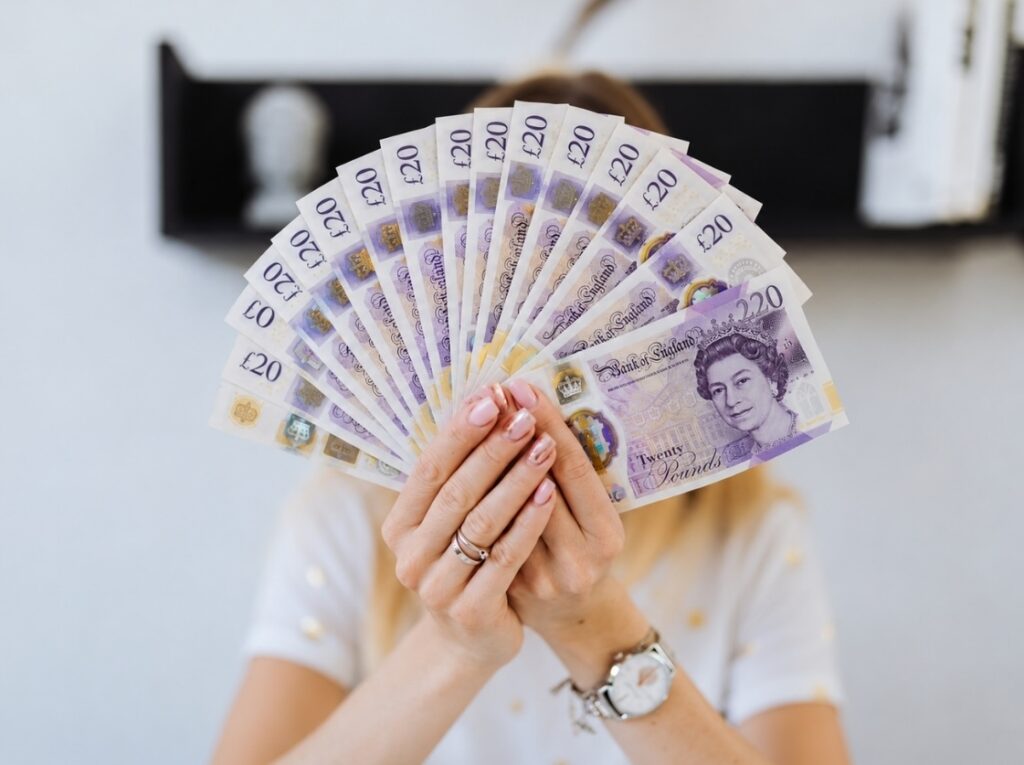 Creative holding a pile of fanned £20 bank notes in her hand to represent cash in business